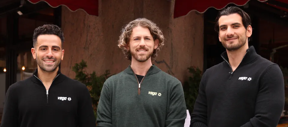 Scott Simkin, Vega’s new Chief Marketing Officer, standing at center with two Vega leaders in Vega quarter-zips outside a New York restaurant.